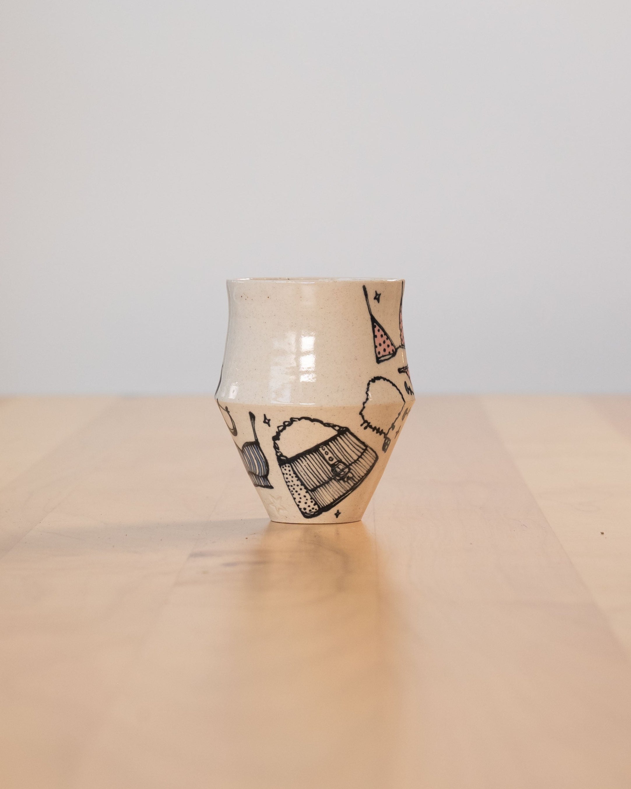 Ceramic vase with black fashion illustrations on a beige surface